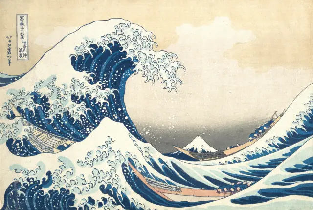 A towering wave curls over three boats, with Mount Fuji in the distance, in Hokusai’s woodblock print.